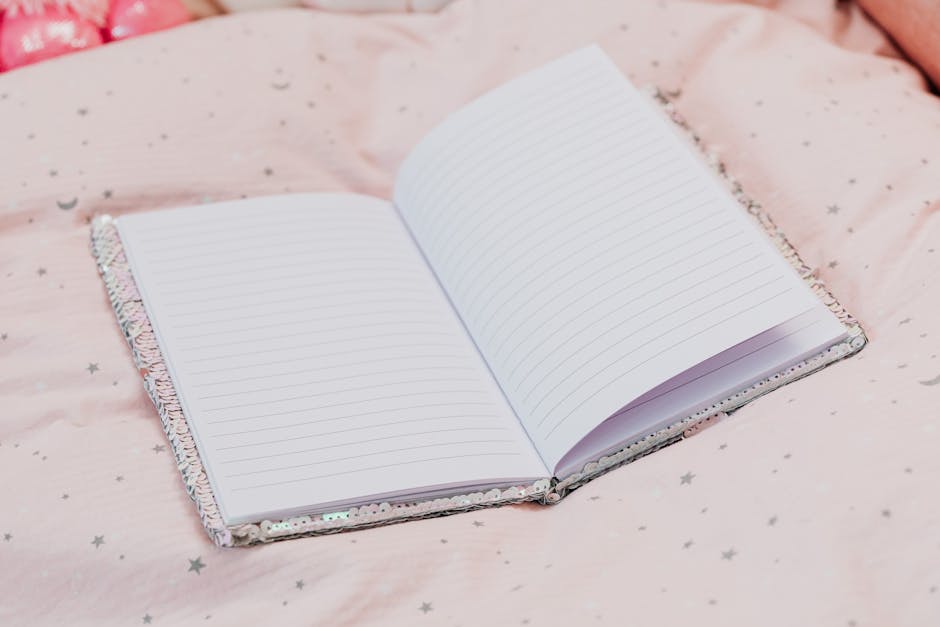 Open notebook with lined pages resting on soft pink star-patterned bedding.