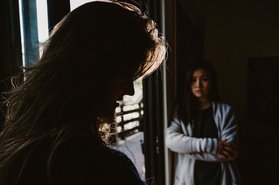 Two women facing a tense emotional exchange in a dimly lit room.