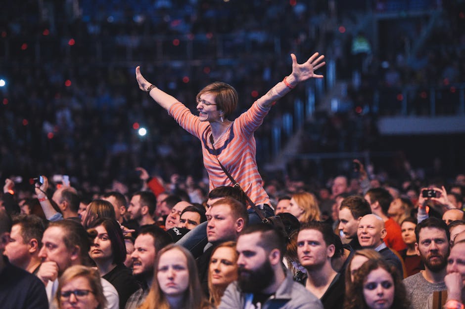 A woman joyfully cheers amidst a lively concert crowd, exuding energy.