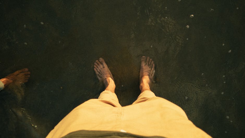 A person standing barefoot in shallow water on a warm summer day.