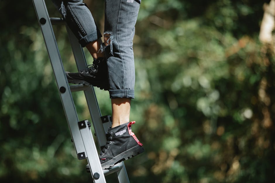 A person wearing black boots and jeans climbs a ladder in a forest, highlighting adventure.