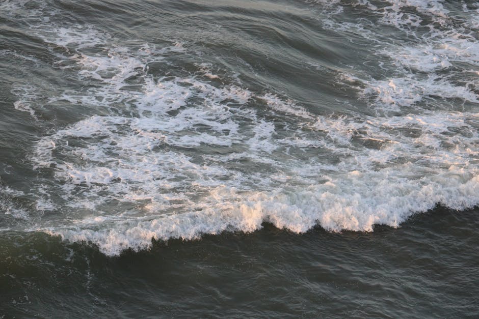 Captivating view of ocean waves with foamy crests crashing on a sandy beach.